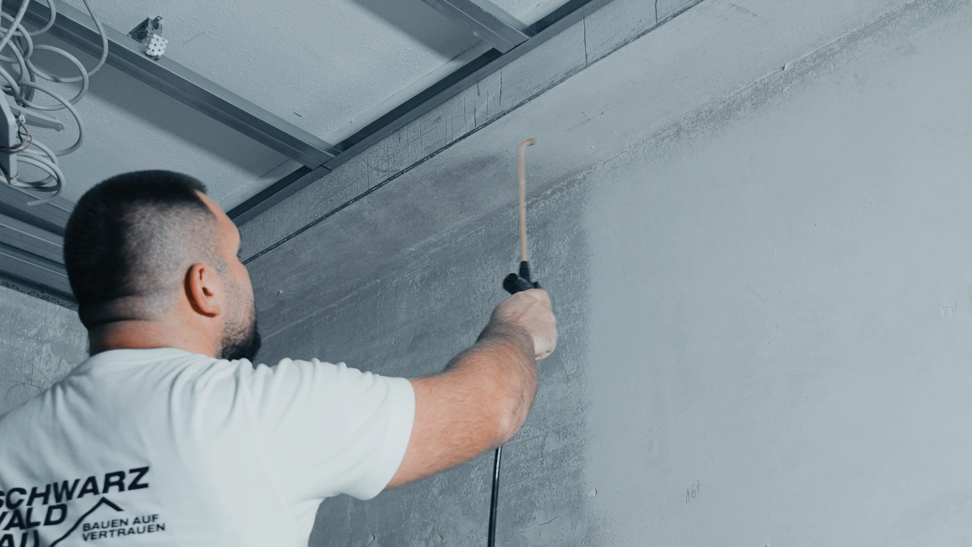 Handwerker der Schwarzwaldbau GmbH verlegt Elektrokabel unter einer Betondecke in Offenburg – präzise Elektroinstallation im Innenausbau