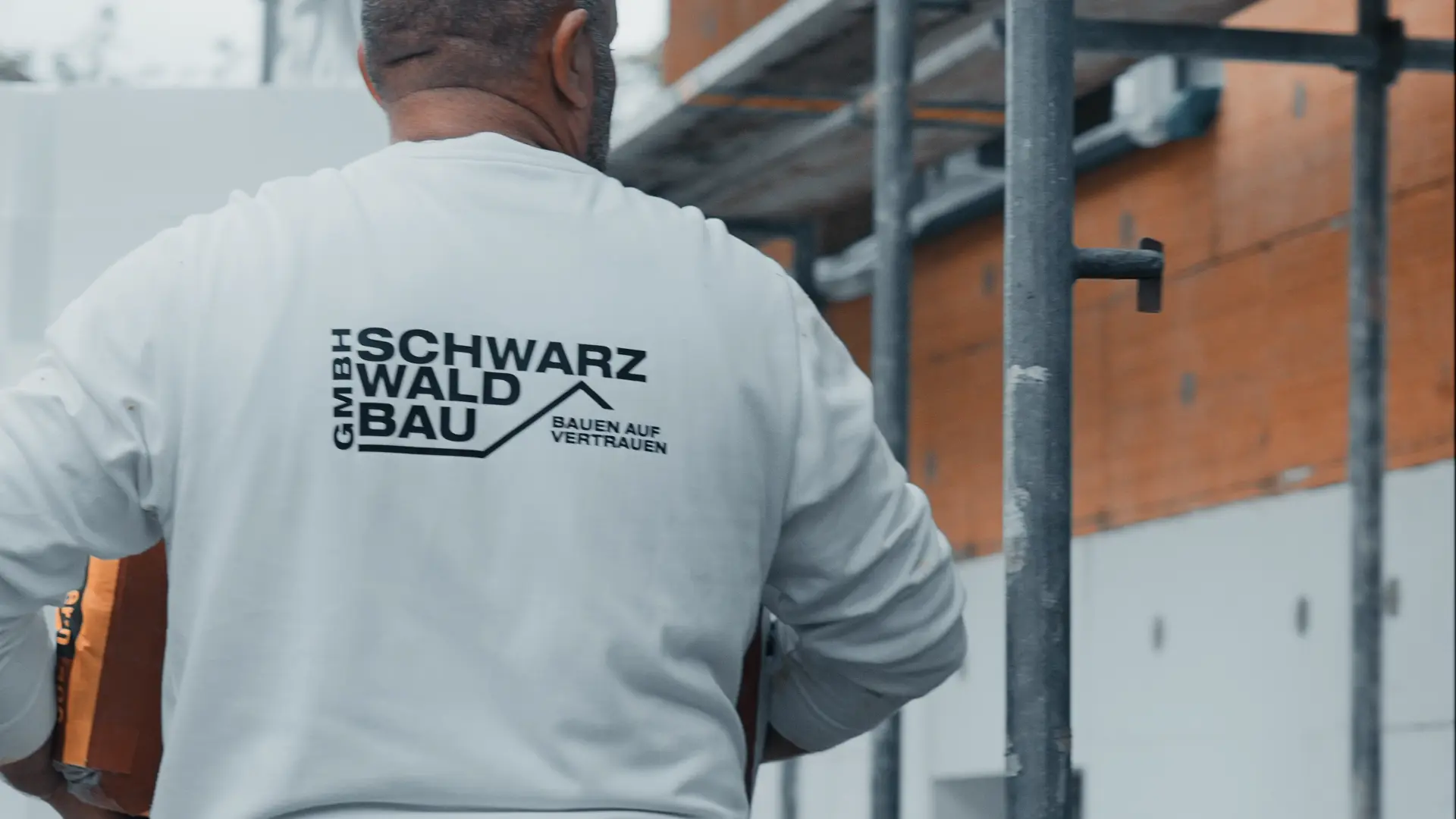 Handwerker der Schwarzwaldbau GmbH auf der Baustelle mit Firmenlogo auf der Arbeitskleidung – regionales Bauunternehmen im Schwarzwald