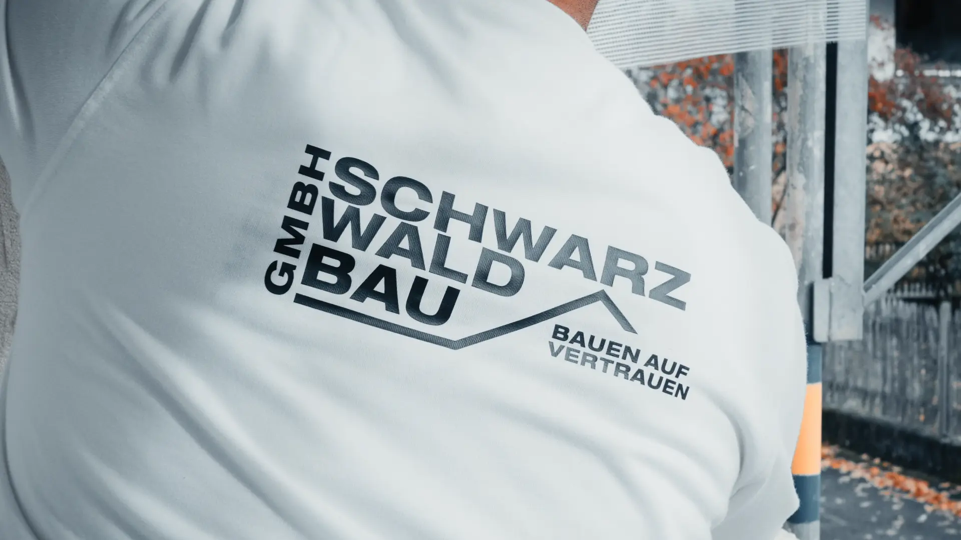 Rückenansicht eines Mitarbeiters der Schwarzwaldbau GmbH mit Firmenlogo auf der Arbeitskleidung – Symbol für regionale Qualität und Vertrauen im Bauwesen