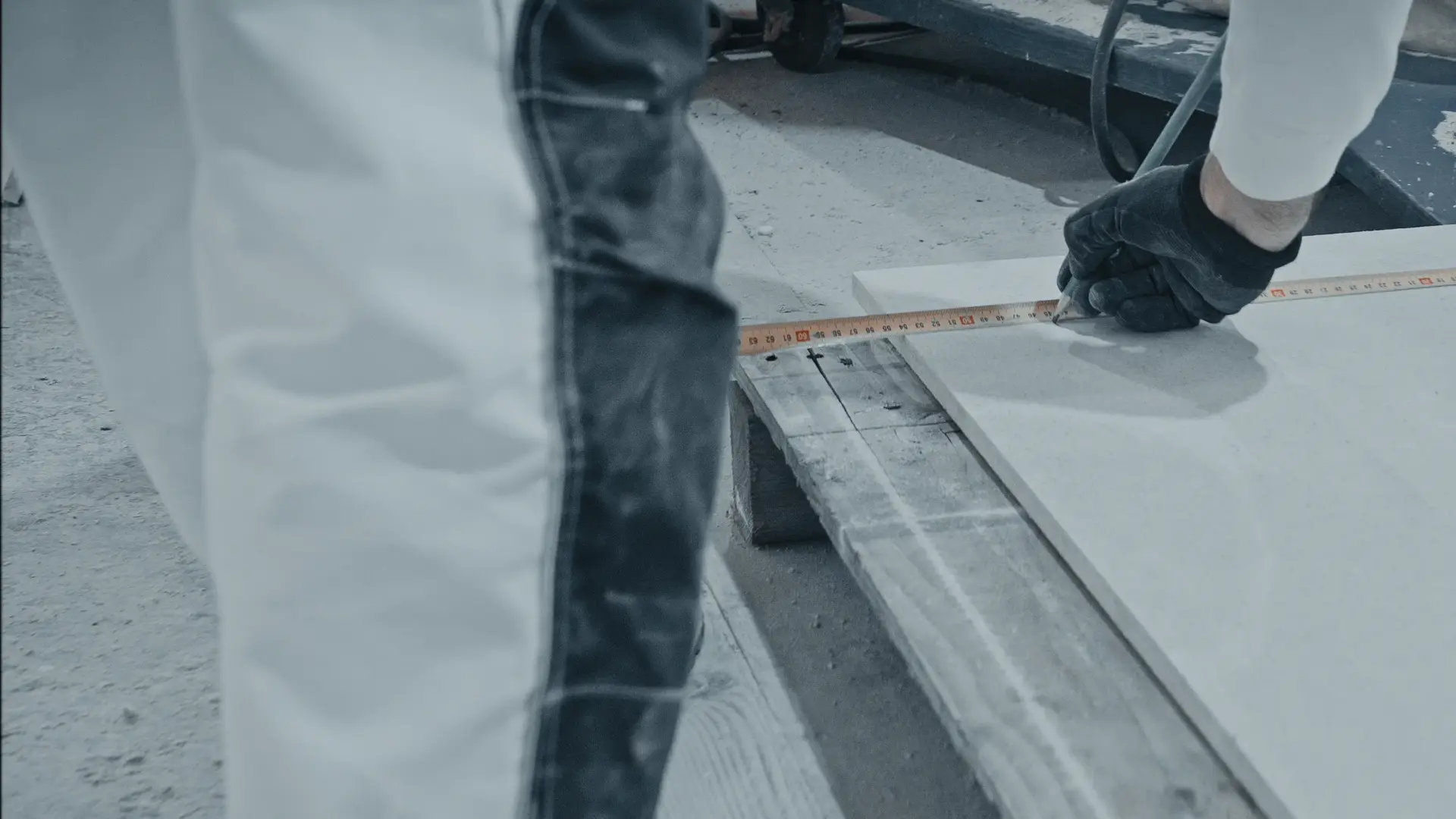 Handwerker der Schwarzwaldbau GmbH misst eine Bauplatte mit Maßband ab – präziser Zuschnitt und Vorbereitung im Innenausbau Schwarzwald