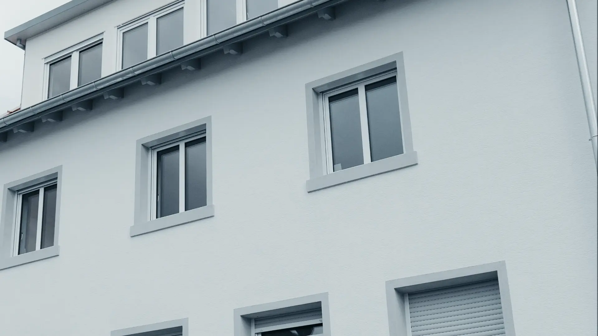 Moderne Außenfassade eines Neubau Wohnhauses der Schwarzwaldbau GmbH mit weißen Putzflächen und grauen Fensterrahmen