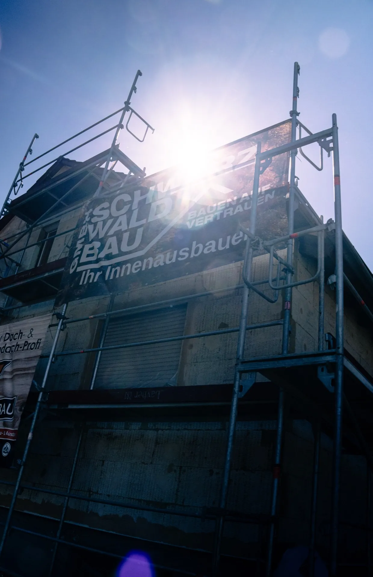 Baugerüst mit Schwarzwaldbau-Banner im Gegenlicht
